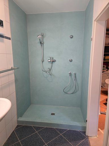 Fugenlose Dusche Dusche mit blauen Wänden, zwei Duschköpfen und einer rutschfesten Bodenfläche.